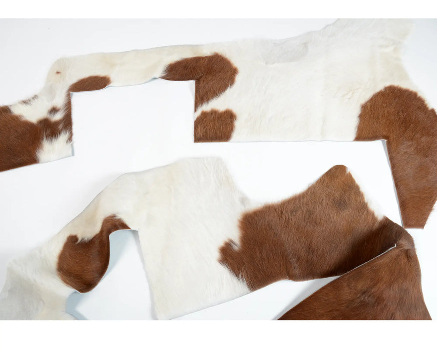 Brown and white cowhide hide pieces for crafting or upholstery.