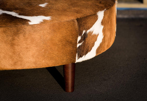 Wood legs on round cowhide ottoman